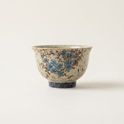Gemini_Generated_Image_iq9wfsiq9wfsiq9w Antique style "Window Flower" ceramic tea cup with hand-applied blue flower patterns and heavy rustic brown speckles, isolated on a white background.