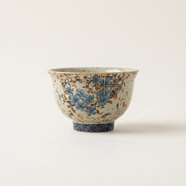 Gemini_Generated_Image_iq9wfsiq9wfsiq9w Antique style "Window Flower" ceramic tea cup with hand-applied blue flower patterns and heavy rustic brown speckles, isolated on a white background.