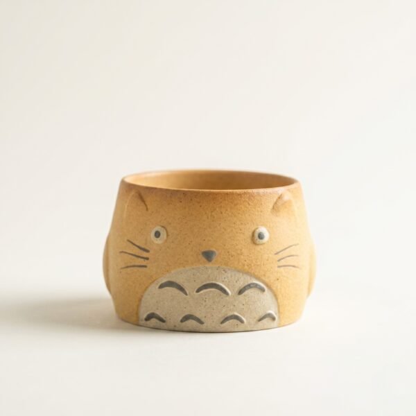 Gemini_Generated_Image_yjsxyuyjsxyuyjsx Handmade earthy brown ceramic totoro tea cup with a cute sculpted face and a grey textured belly, isolated on a white background